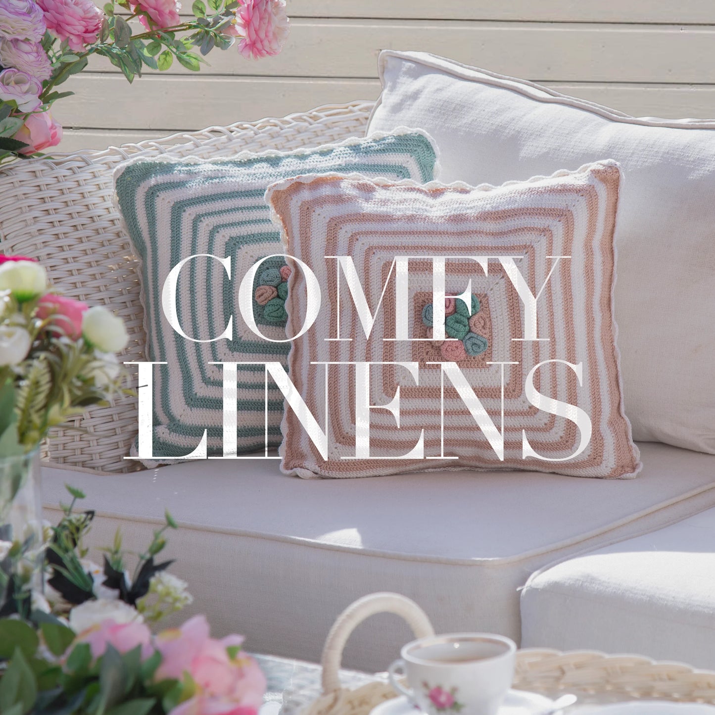 Cozy white wicker sofa with two striped crocheted pillows and fresh flowers on a sunlit patio