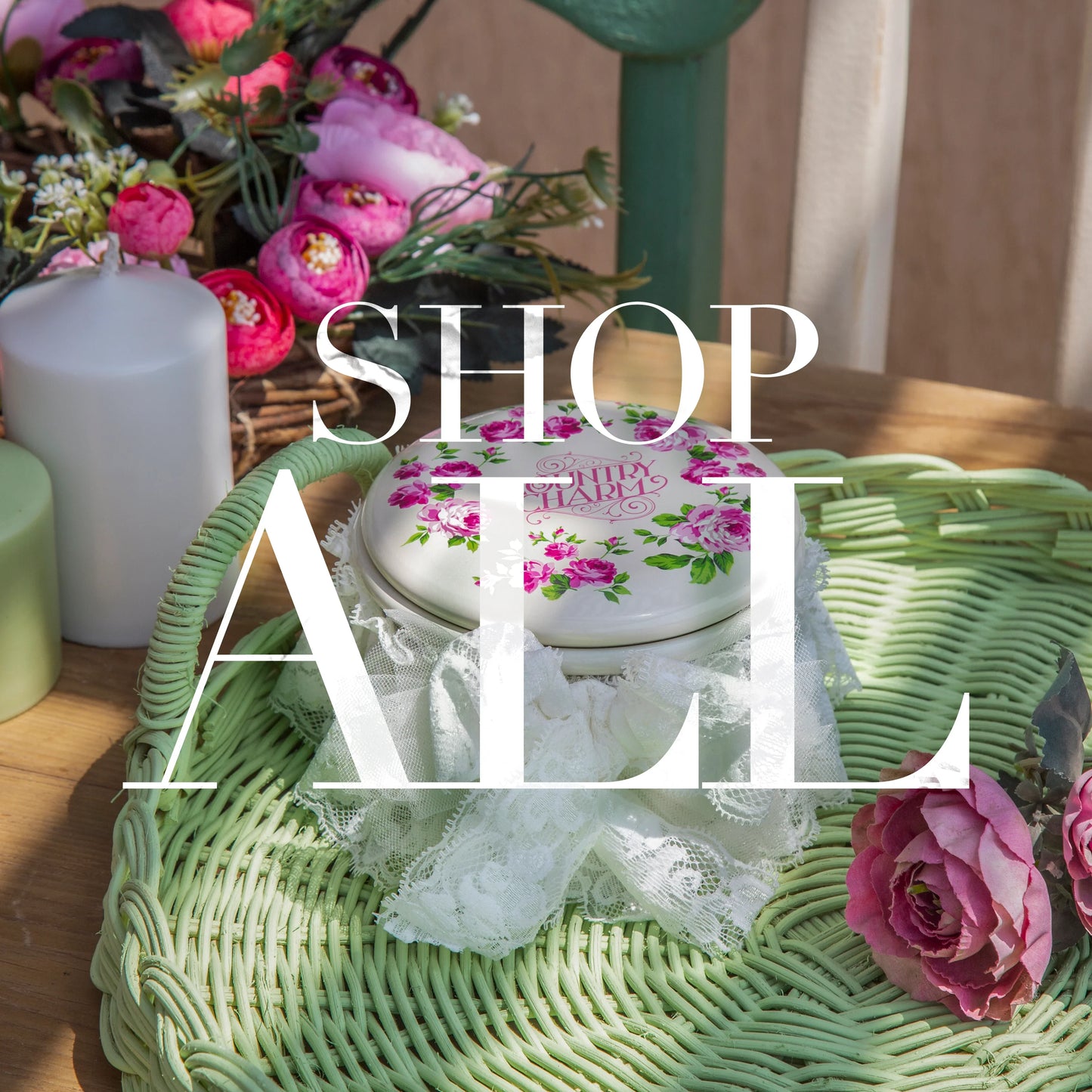 Floral tin container on green wicker tray with pink roses and white candles, shop sale text overlay