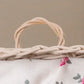 Close-up of woven light brown wicker basket handle with white fabric and floral pattern