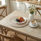 Breakfast scene with a plate of croissant, berries, and a cup of coffee on a wooden table.