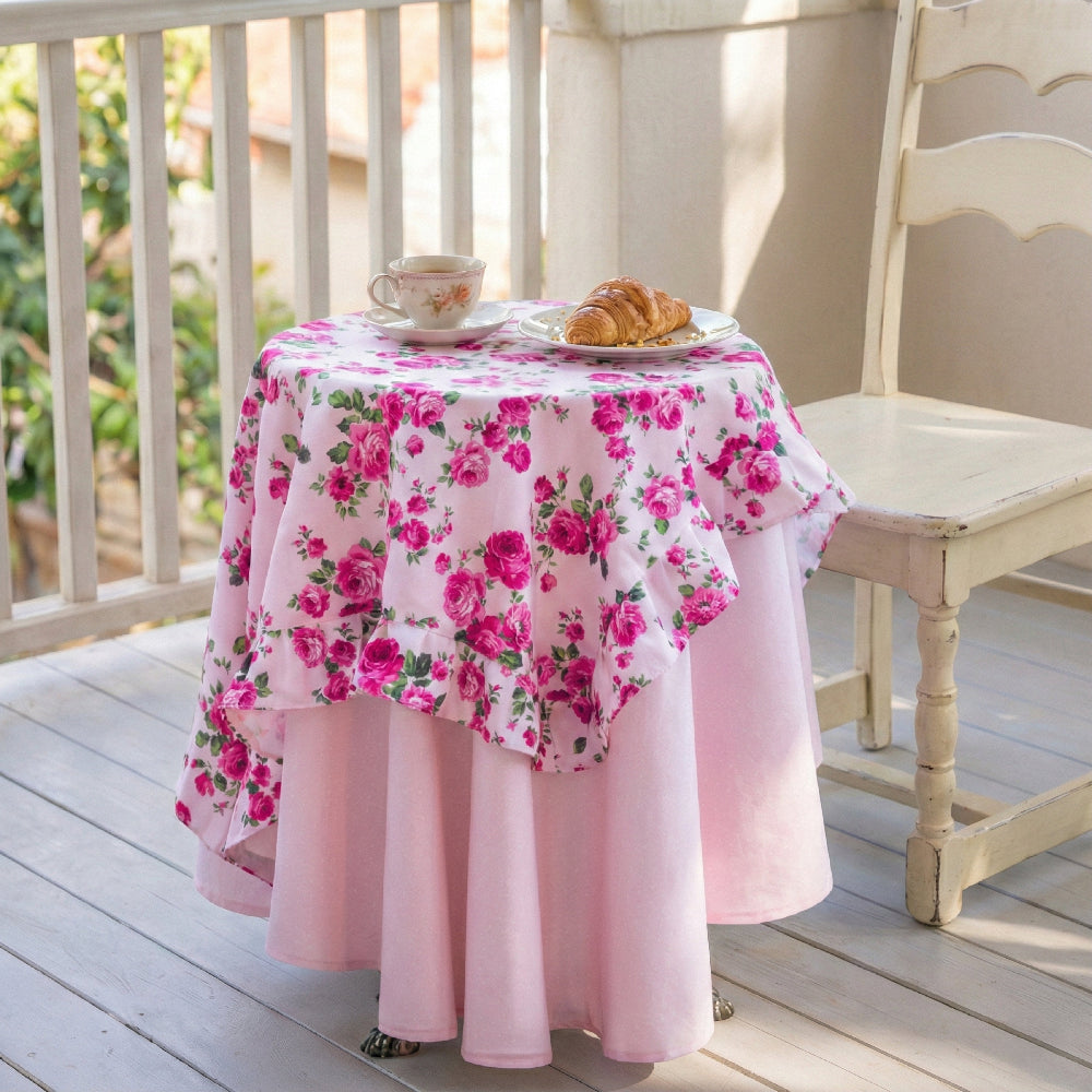 Round table with pink floral tablecloth on a wooden deck