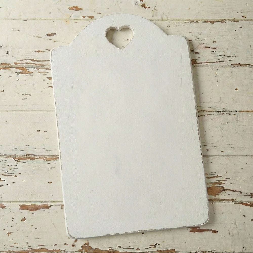 White cutting board with a heart-shaped hole on a wooden surface