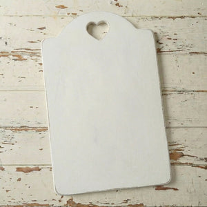 White cutting board with a heart-shaped hole on a wooden surface