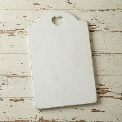 White cutting board with a heart-shaped hole on a rustic wooden surface