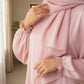 Person wearing a pink outfit with a matching hijab indoors.