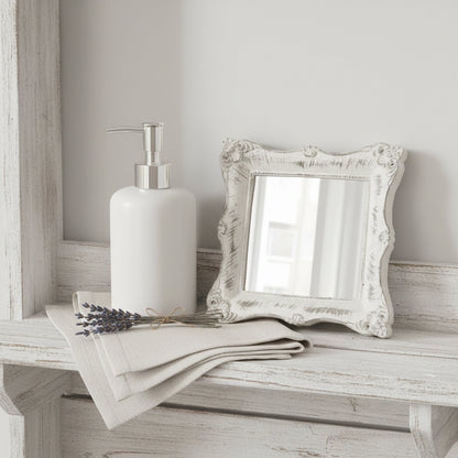 Ornate antique white square mirror on a distressed wood shelf with vintage keys and a small dried flower.