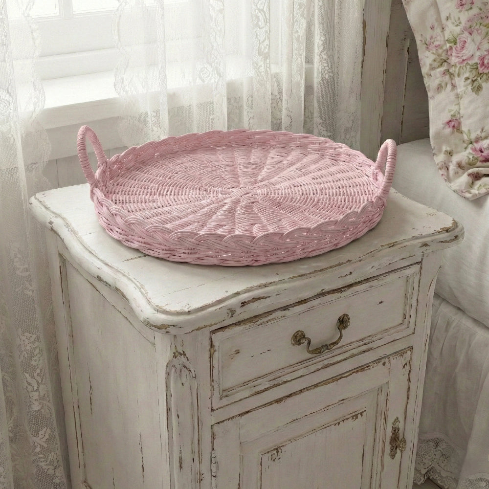 Pink Round Wicker Tray on a distressed wooden cabinet with floral curtains in the background