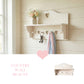 Wooden wall shelf with heart-shaped cutout and hooks holding keys and fabric, and a small plant on a shelf.