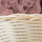 Close-up of woven light-colored wicker basket with patterned fabric background