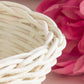 Close-up of white woven wicker basket edge with pink flower petals in background