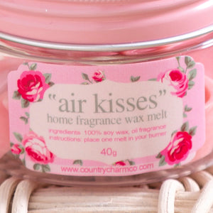 Close-up of pink label on glass jar for "air kisses" home fragrance soy wax melt with floral design