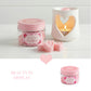 Pink jar of 'air kisses' with heart-shaped candles on a white background

