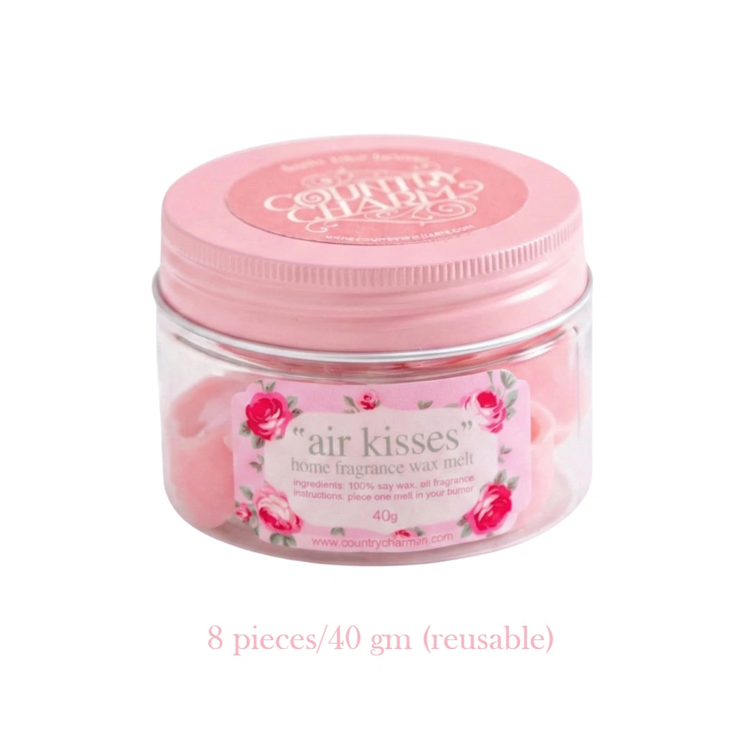A clear jar with a pink lid containing Air Kisses home fragrance soy wax melts against a white background.