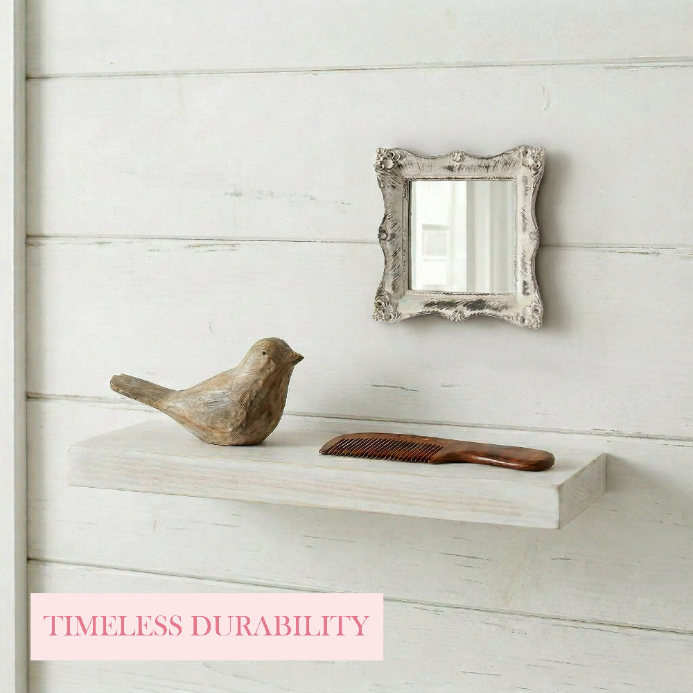 Antique white mirror on a plank wall above a floating shelf holding a wooden bird figurine and a brown comb.