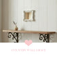 Small antique white ornate mirror hanging on a white wood plank wall above a rustic shelf with iron brackets.