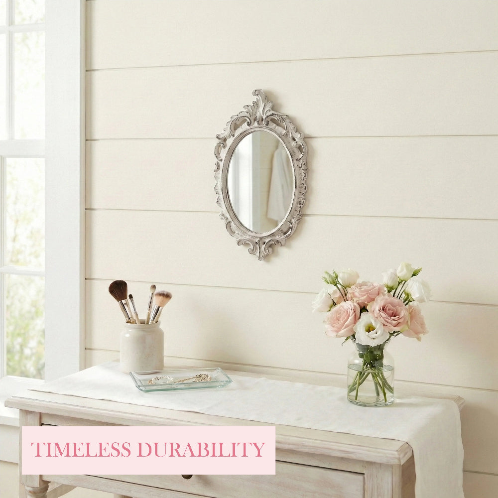 Ornate oval mirror on a shiplap wall above a vanity with makeup brushes, a glass tray, and pink flowers in a vase.