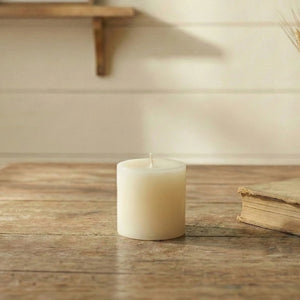 Antique White Pillar Candle on wooden surface in home decor styling with blurred background