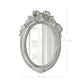 Antique white oval mirror with a ribbon crest on a white background with pink dimension lines and text.