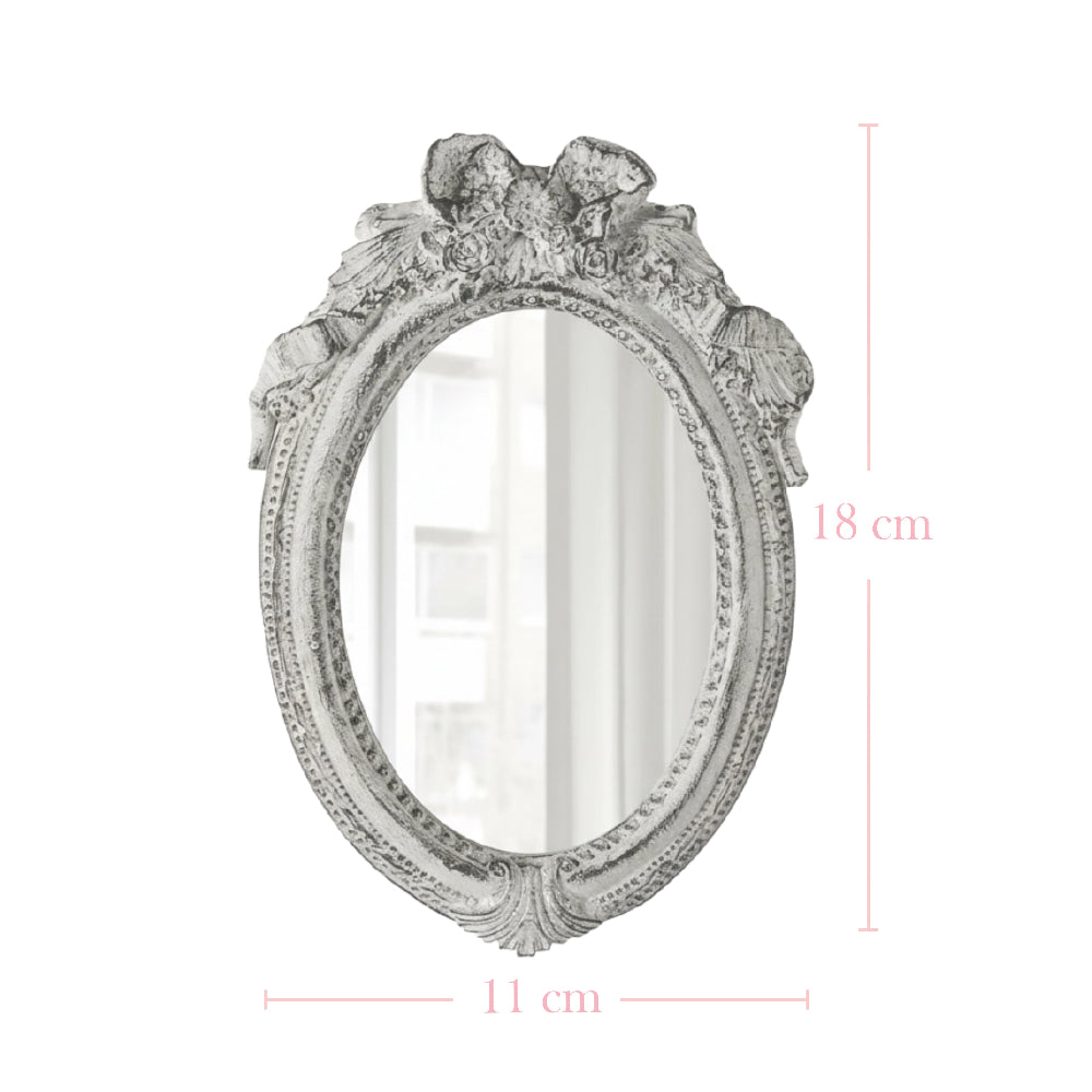 Antique white oval mirror with a ribbon crest on a white background with pink dimension lines and text.