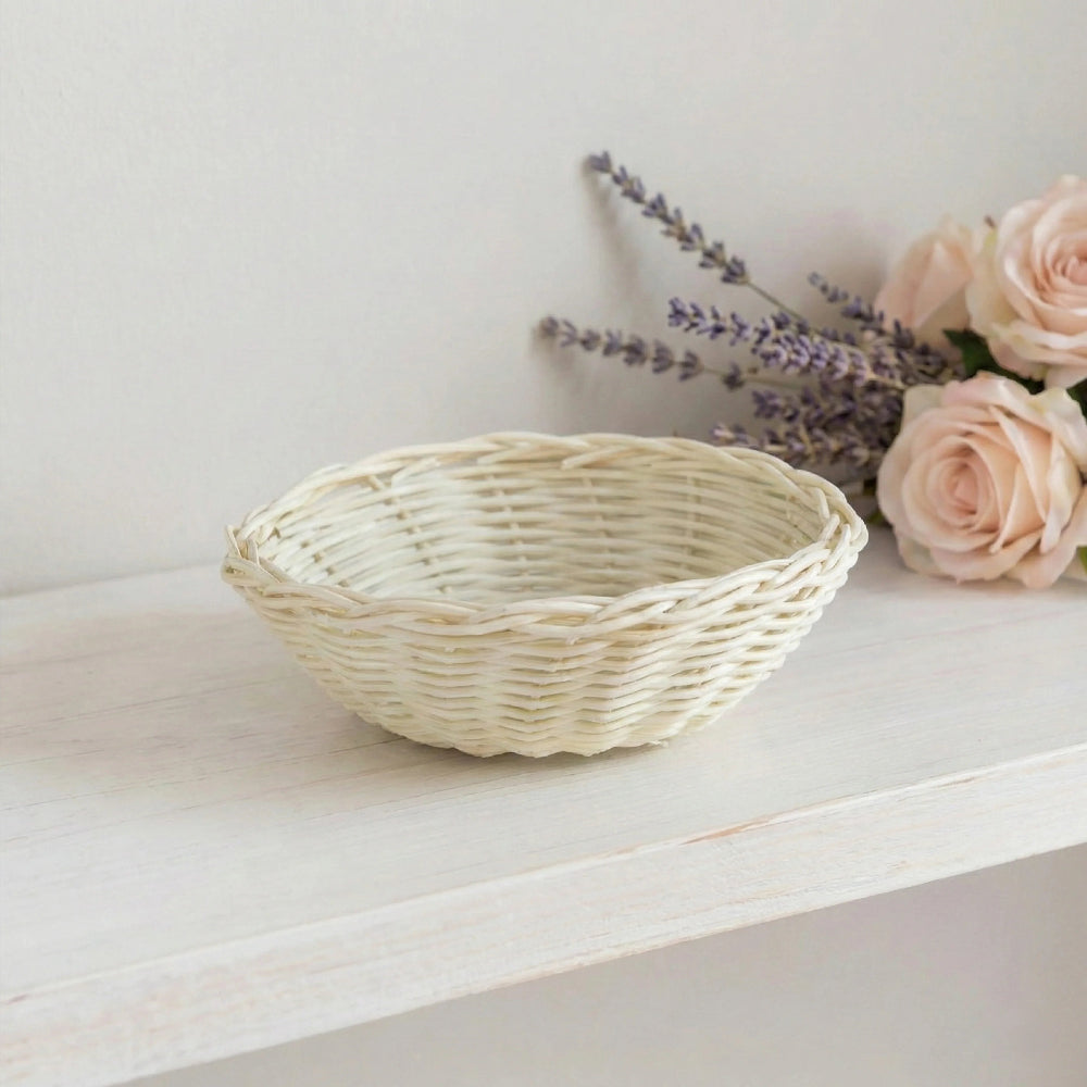 Antique white wicker basket on a whitewashed wooden shelf with lavender and pink roses in the background.