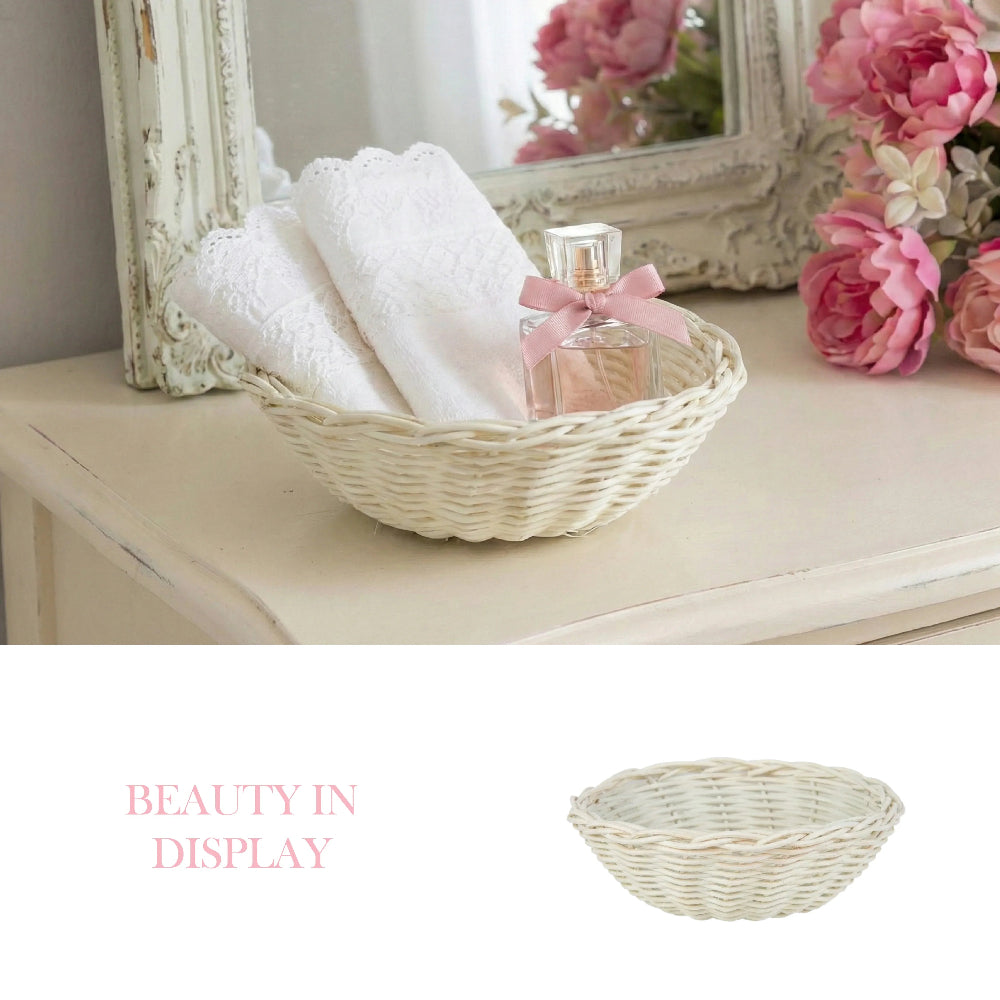 Antique white wicker basket on a vanity with lace towels and perfume, positioned next to pink flowers and a mirror.