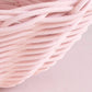 Close-up of a pink woven wicker basket against a pink background