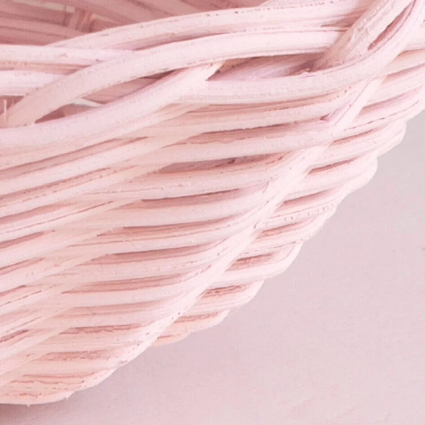 Close-up of a pink woven wicker basket against a pink background