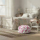 Bedroom with floral bedding and pouf ottoman in a cozy setting