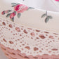 Close-up of a pink Cottage Round Wicker Basket with floral fabric and lace trim.