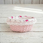 Cottage Round Wicker Basket with floral lace linen lining displayed on wooden surface