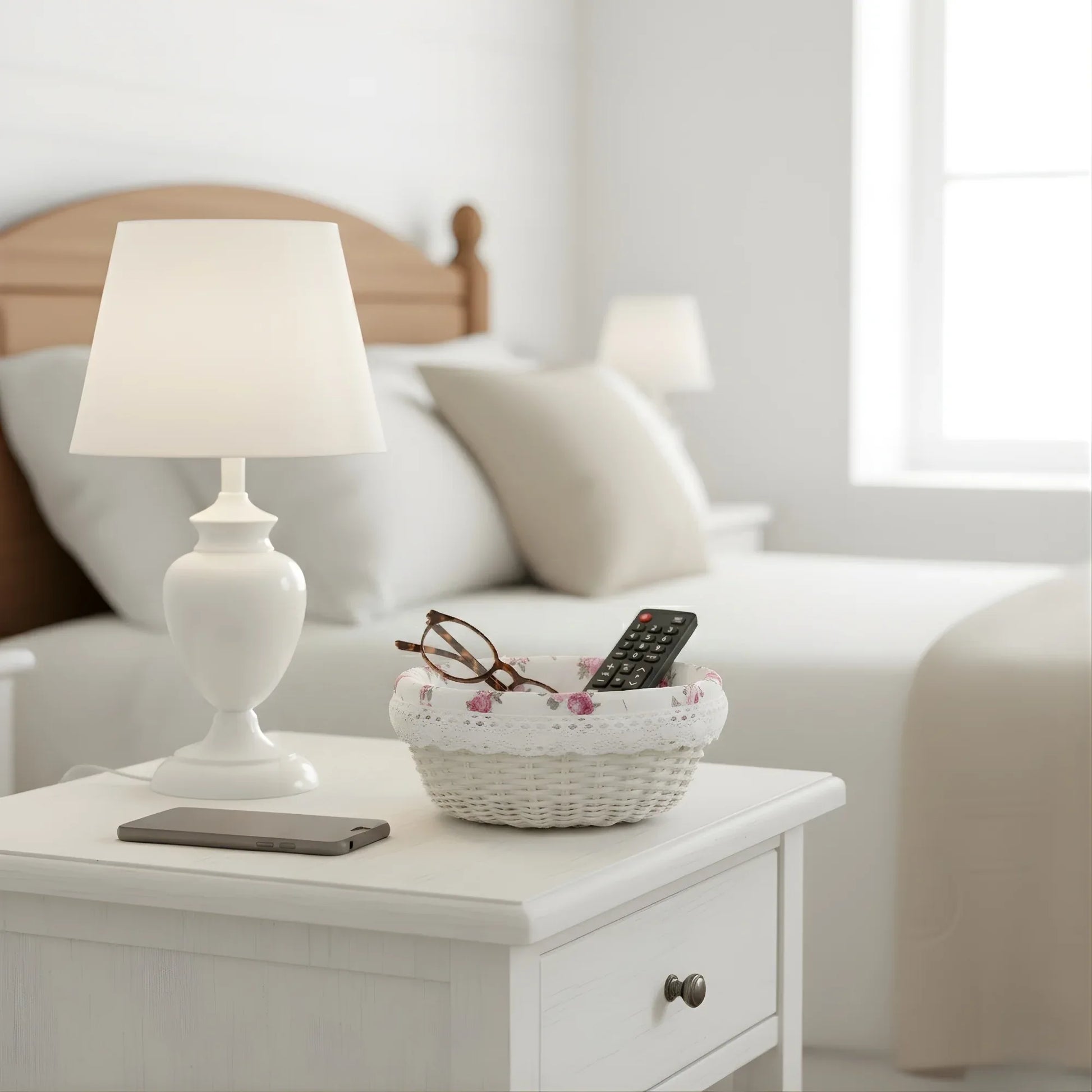White lamp on a nightstand next to a bed with pillows