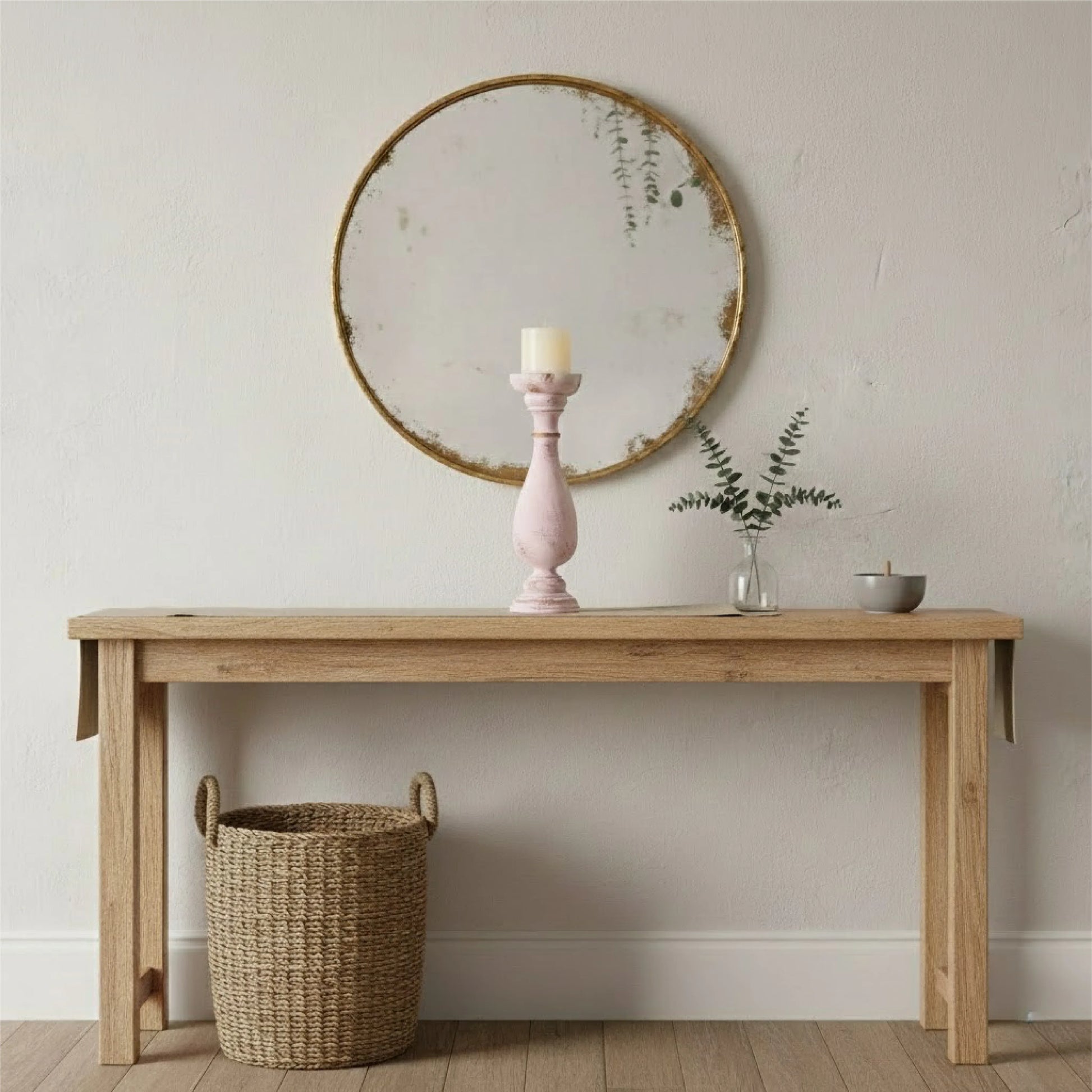 Wooden console table with a round mirror, candle, and basket in a room.