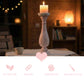 Wooden candle holder with a lit candle on a table in a cozy room.