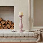 Pink candle holder with a candle on a fireplace mantle