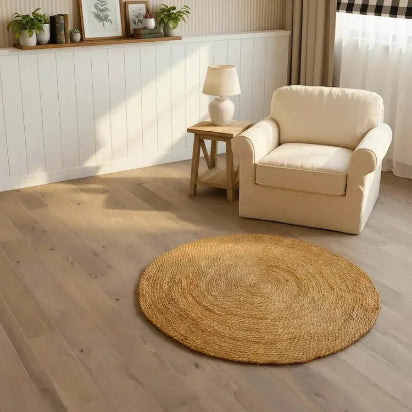 Country Charm Halfa Round Rug handcrafted in Egypt beside beige armchair on wooden flooring