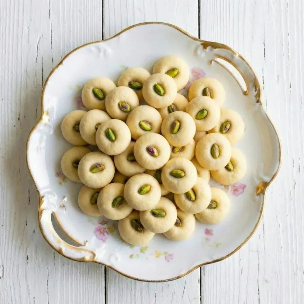 Country Charm Signature Ghorayeba Cookies with pistachios on white wooden surface Eid treats