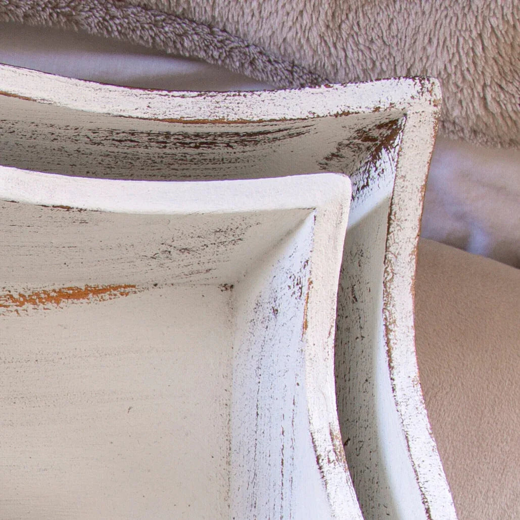 Close-up of rustic white distressed wooden trays stacked on neutral textured fabric