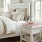 Country heart cut-out pale pink tray in Neatly made bed with white bedding and pillows in a bright bedroom.