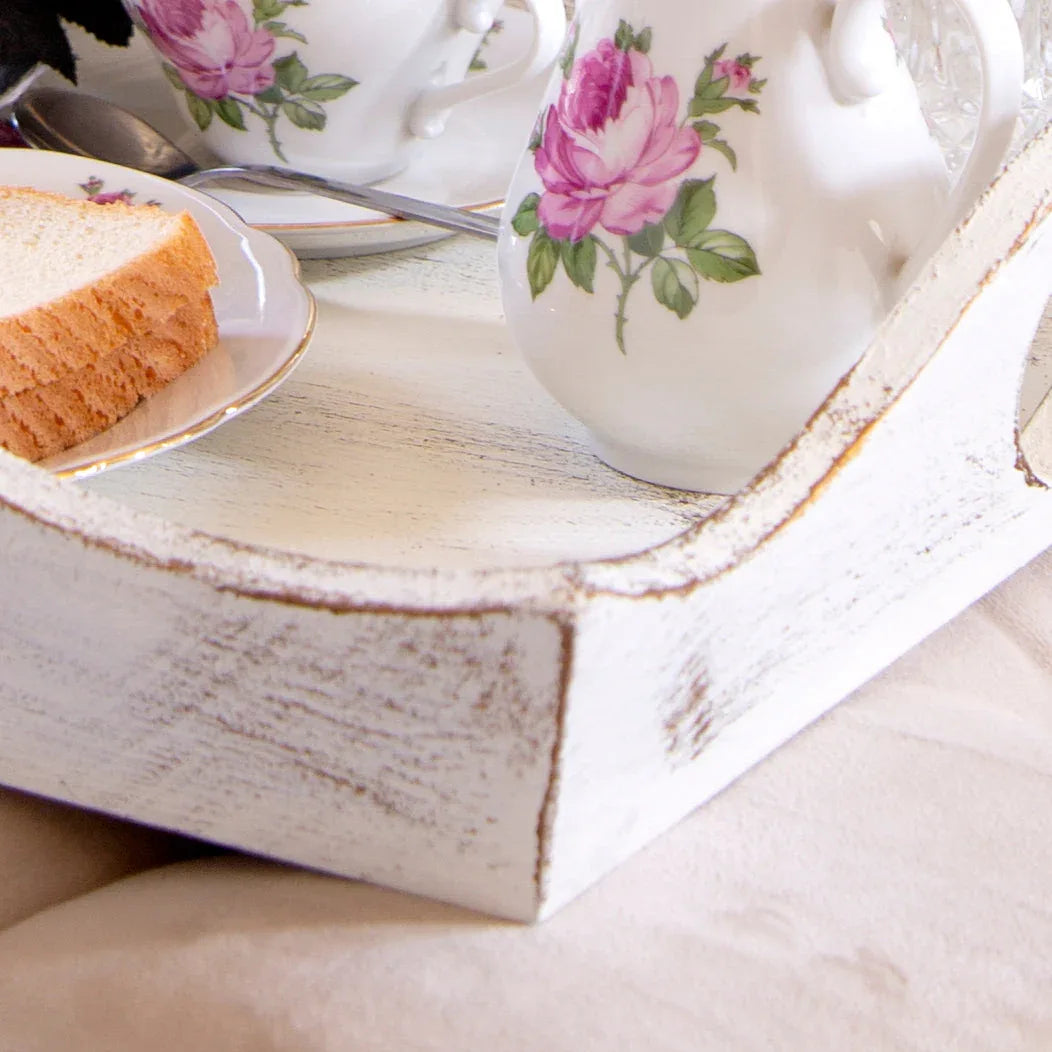 Vintage tea set with pink rose pattern on white distressed wooden tray with sliced bread