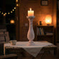 Candle in a decorative holder on a wooden table with a warm, cozy ambiance.