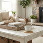 Cozy living room with a wooden coffee table, books, a cup, and plants.