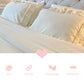 Close-up of cream ruffled pillows on a bed with pink icons for soft, durable, lightweight, and breathable features.