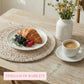 Breakfast scene with croissant, berries, and coffee on a wooden table.