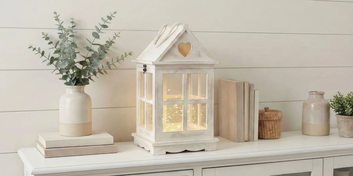 Decorative house-shaped lantern with books and plants on a white surface