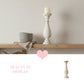 Decorative shelf with a candle holder, bowl, and towel against a plain wall.