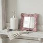 Distressed pink ornate mirror on a white wooden shelf next to a soap dispenser and dried lavender on a linen cloth.