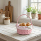 Pink wicker basket with bread on a wooden table in a bright kitchen.