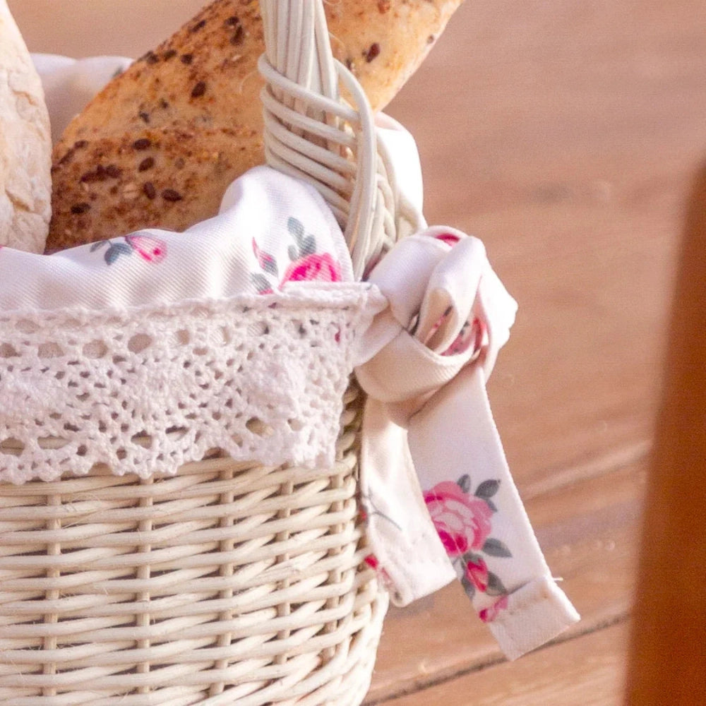 Farmhouse Wicker Basket Round with Handles antique white filled with bread and floral ribbon on wooden surface