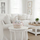 White living room with a wicker basket on a small round table.

