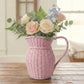Pink wicker pitcher filled with flowers on a wooden surface